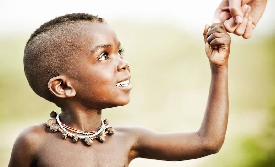 Smiling African child holding a person's hand