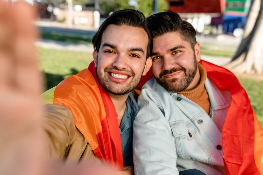 Happy young men wrapped in a gay pride flag