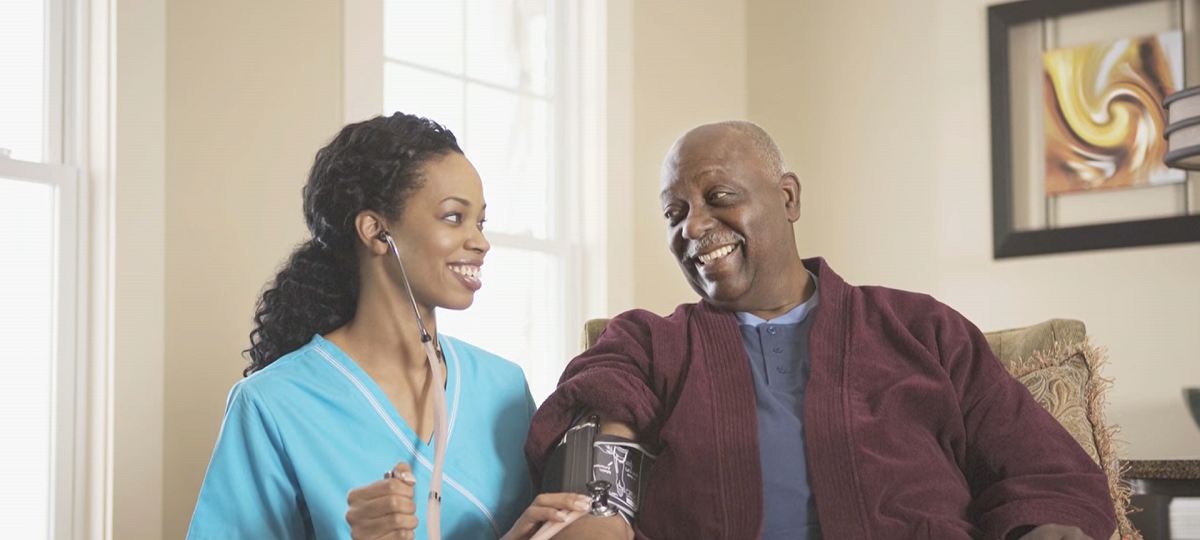 a nurse checking a mature man's blood pressure at home