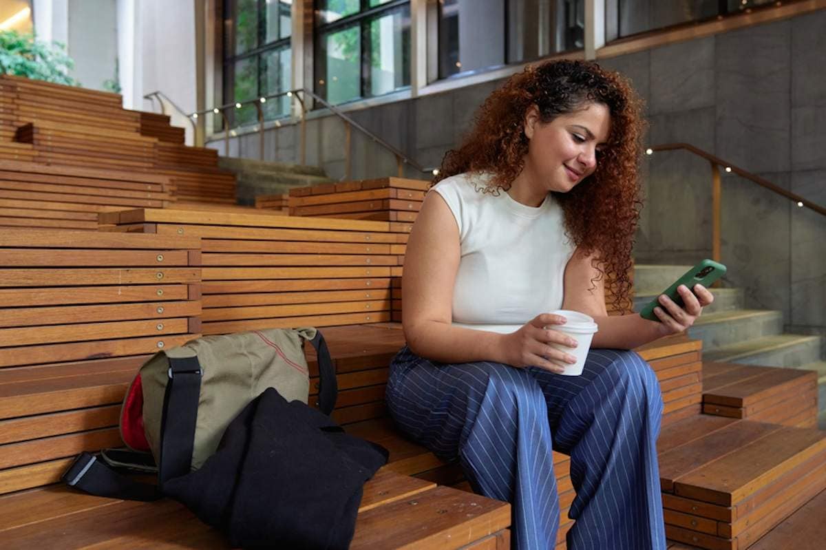 Woman sitting on steps looking at phone