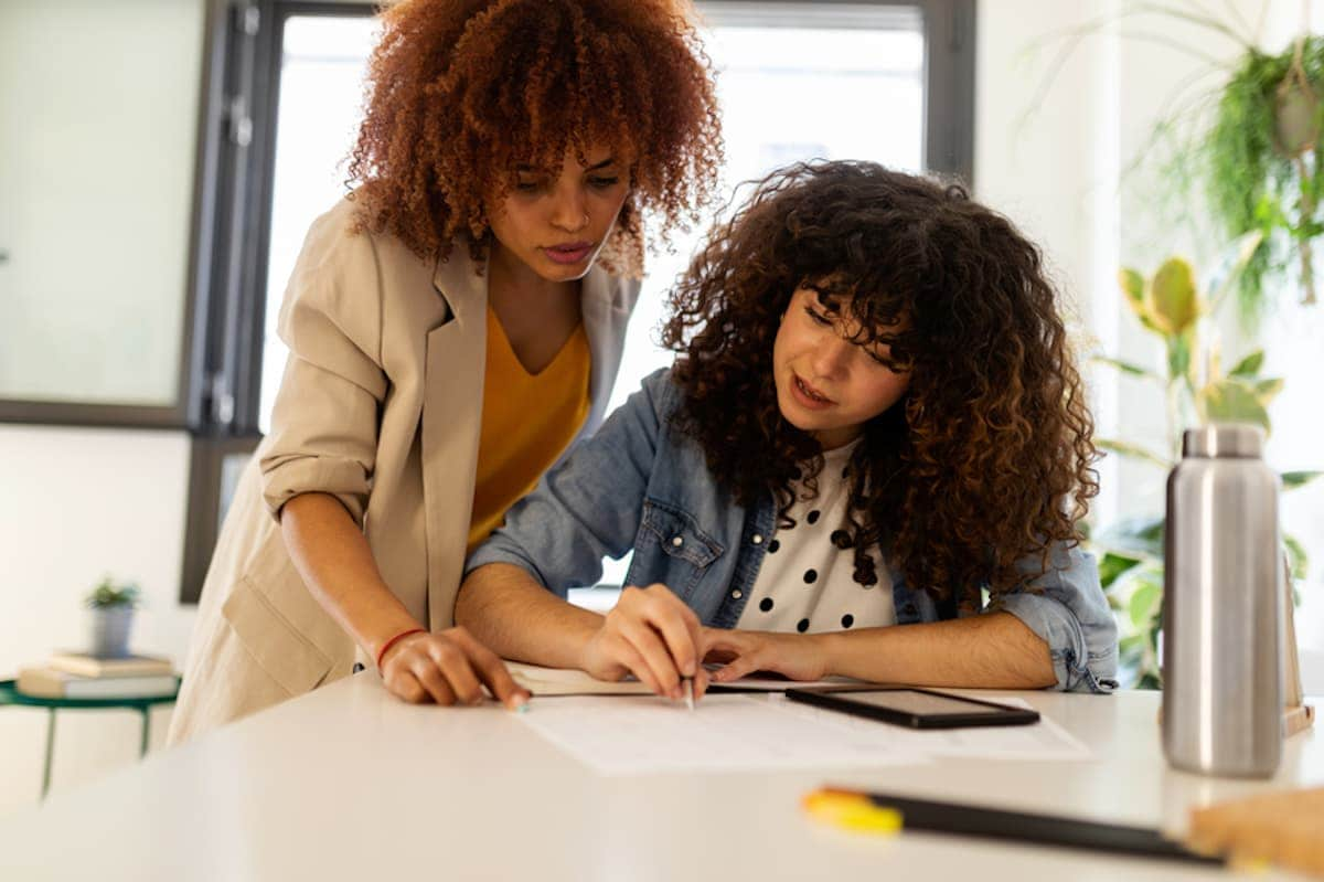 Two professional women work together at a desk.