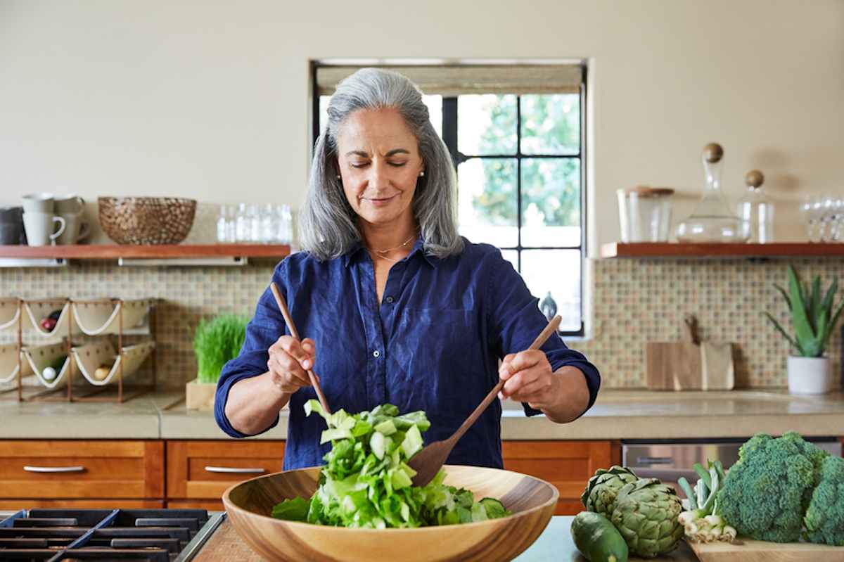Mature woman tosses a healthy salad in the kitchen of her home