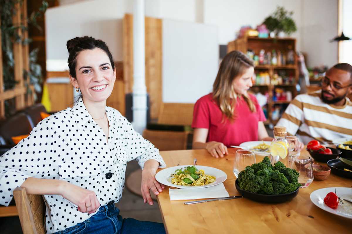 A young woman smiles for the camera at a dinner party