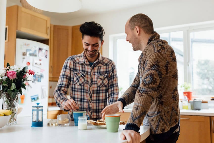 Two men talking and having coffee together in the kitchen.