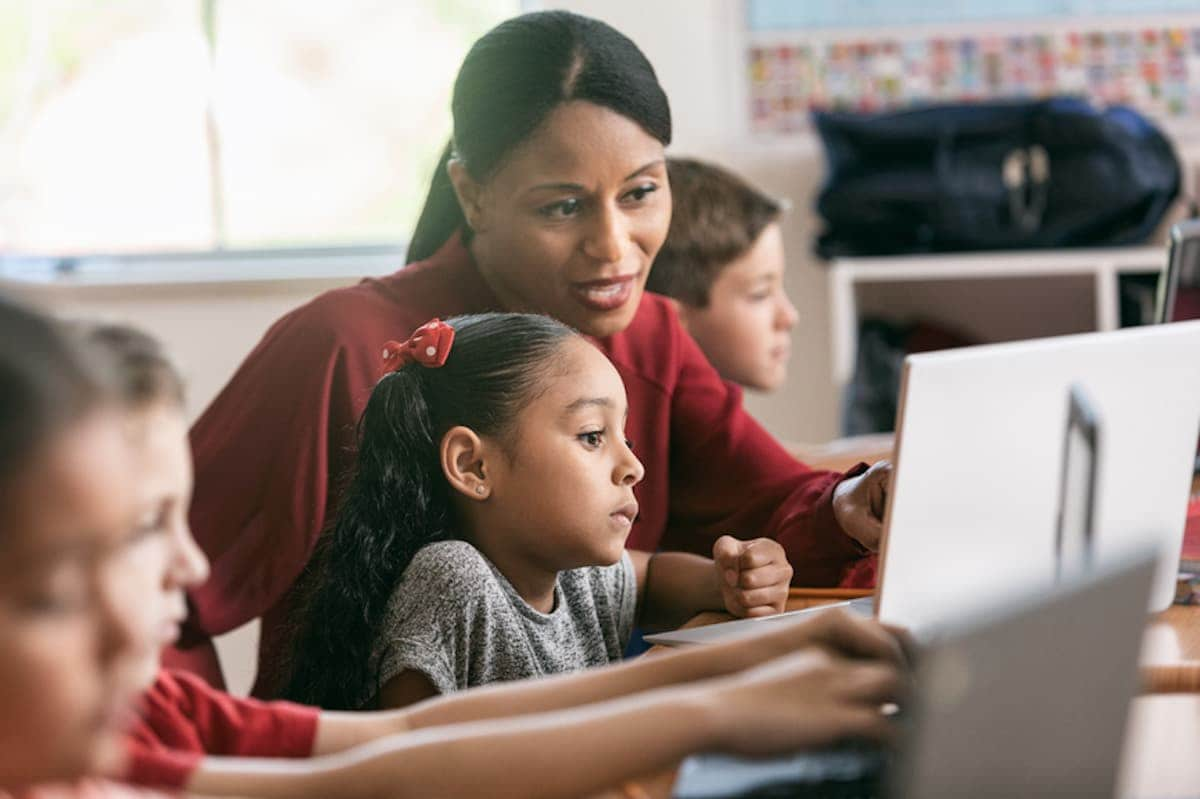 A teacher assists students in a classroom.