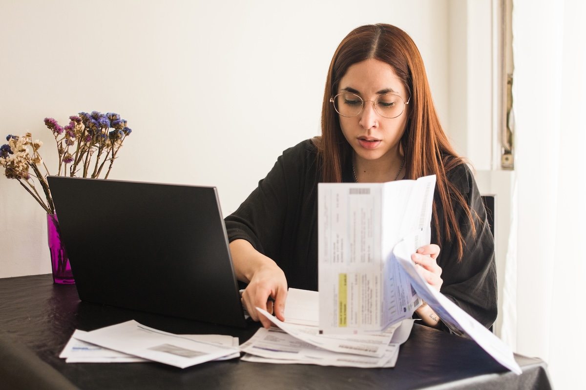 A person sitting at a desk with a laptop and paper.