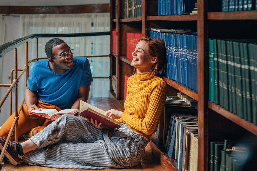 Students laughing while reading together in the library