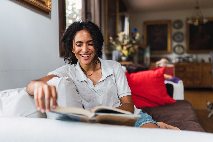 Smiling woman reading a book on the sofa.