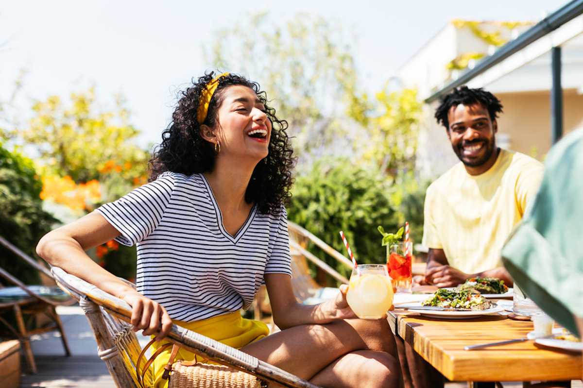 Stylish young woman laughs at outdoor café in summer