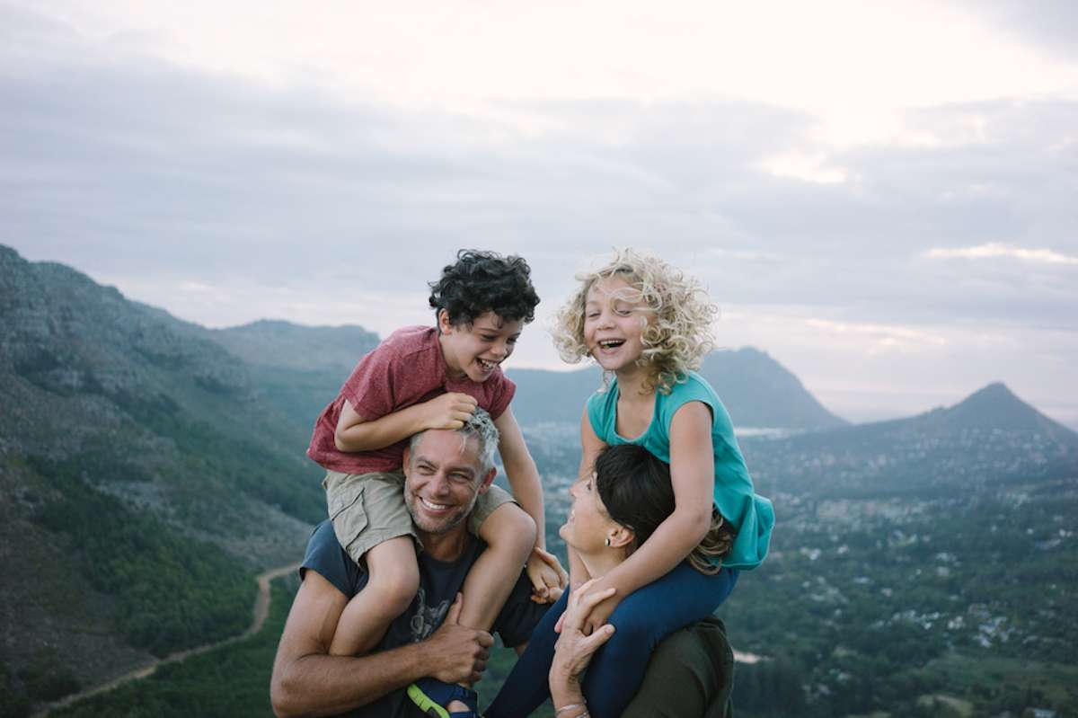 Parents give their two children piggy-back rides on a hike in the mountains