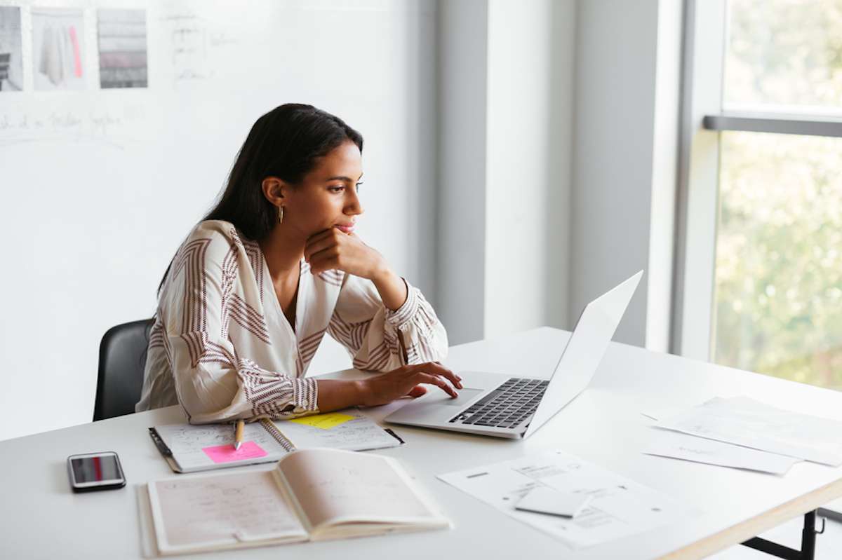 Female event planner uses laptop at desk in contemporary office