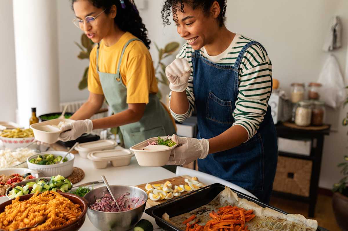 Two female cooks prepare healthy food for lunch boxes