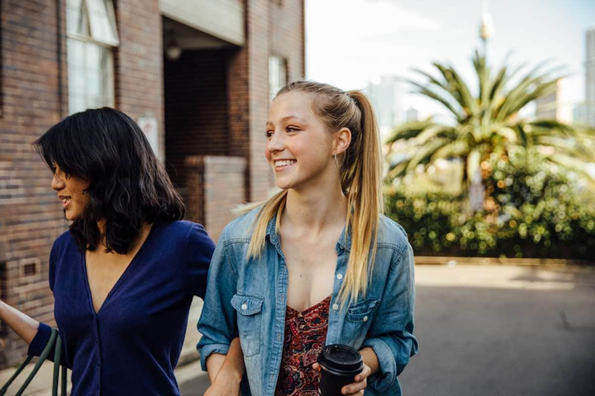 Two young female friends stroll down the street