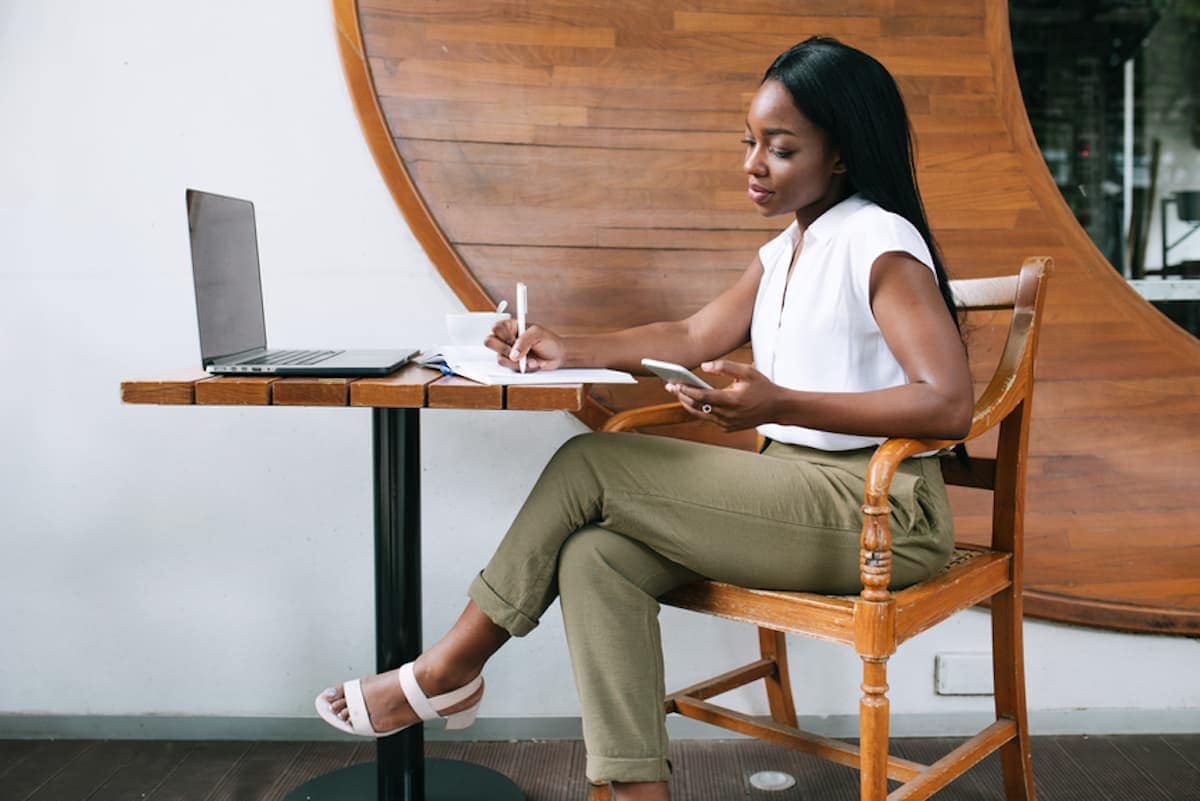 A young Black professional woman seated at a table looks over paperwork.