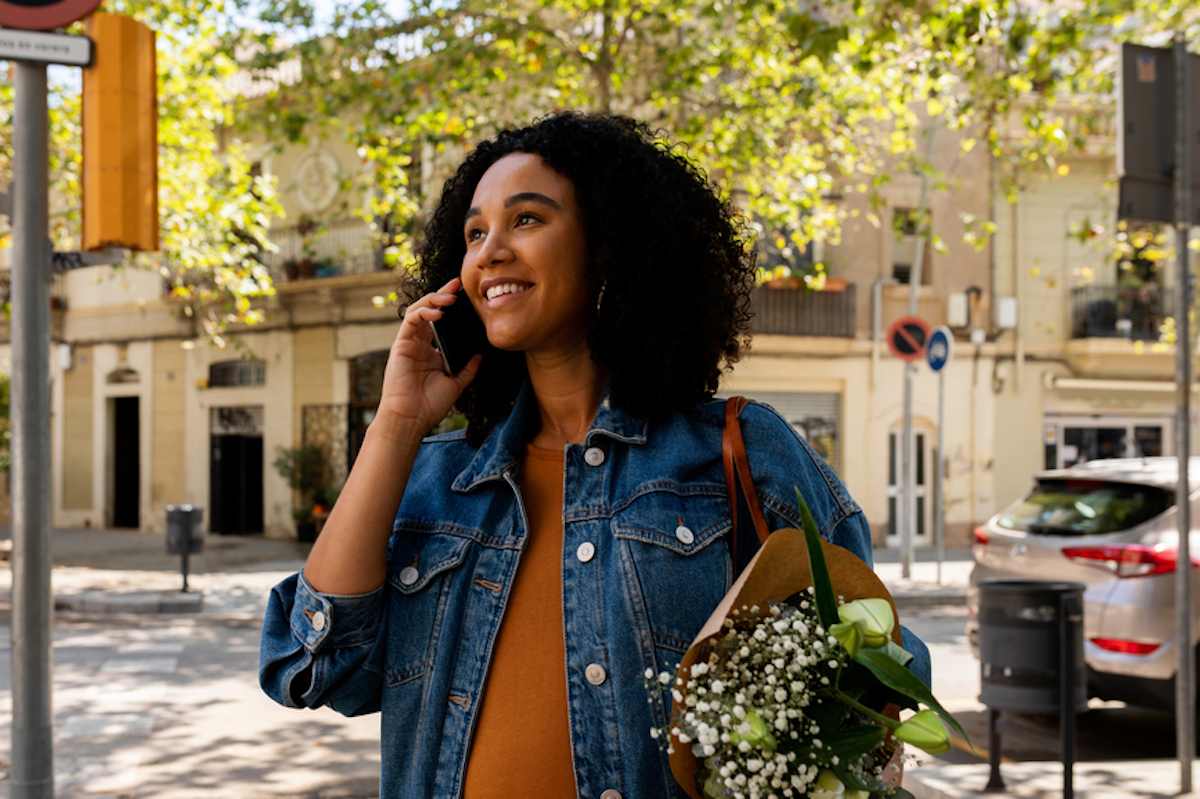 Pregnant woman holding flowers speaks on a smartphone