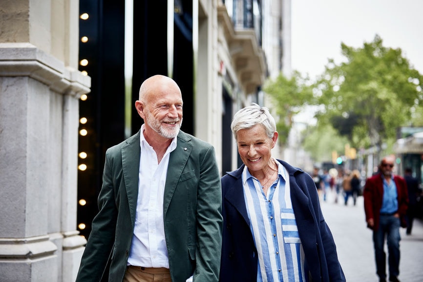 Happy senior couple walking on sidewalk in city