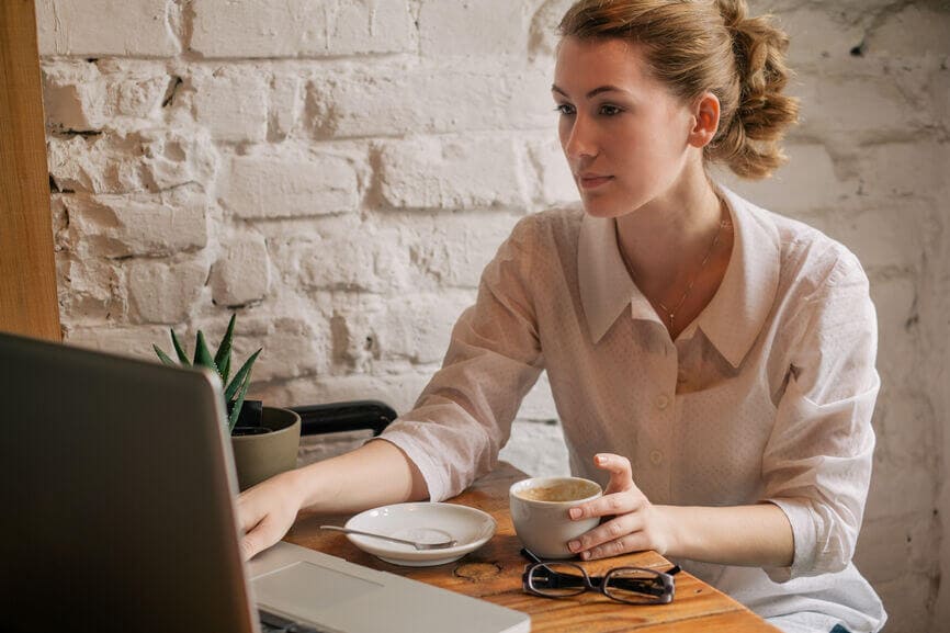 woman drinking coffee and working on her laptop
