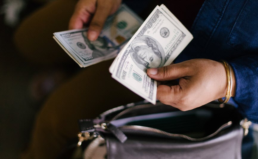 Woman counting cash and putting it in her purse