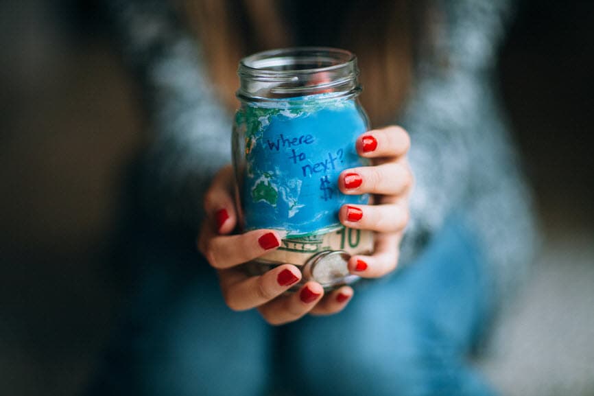 Hands holding jar of money with the label "where to next?"