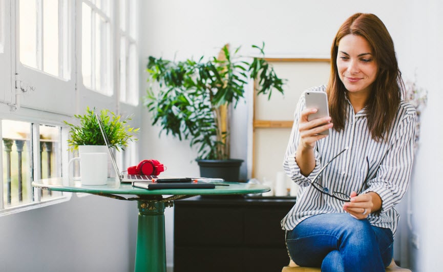 Woman on her smartphone sitting at her desk
