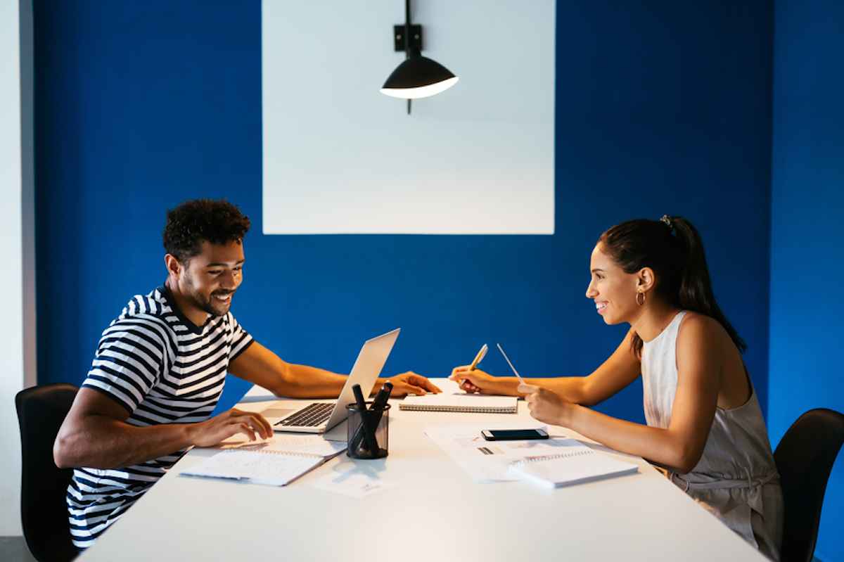 Cheerful couple using laptop and taking notes