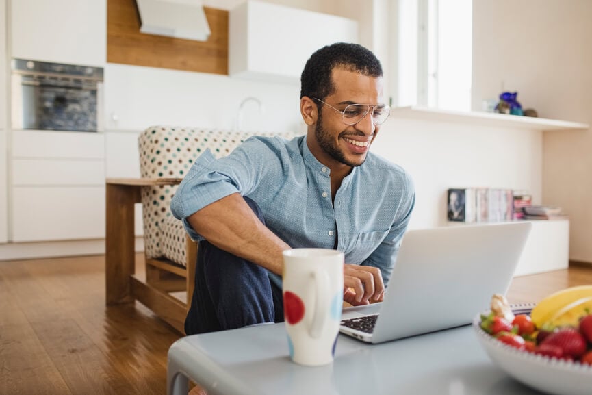 Man smiling at open laptop with coffee