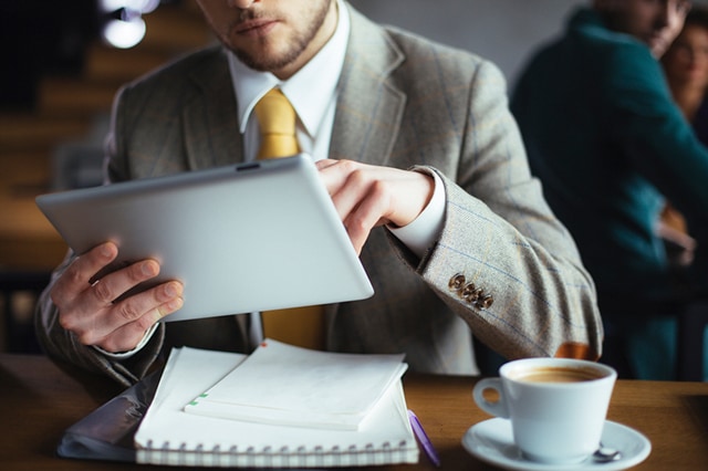 Person in suit working on tablet with coffee