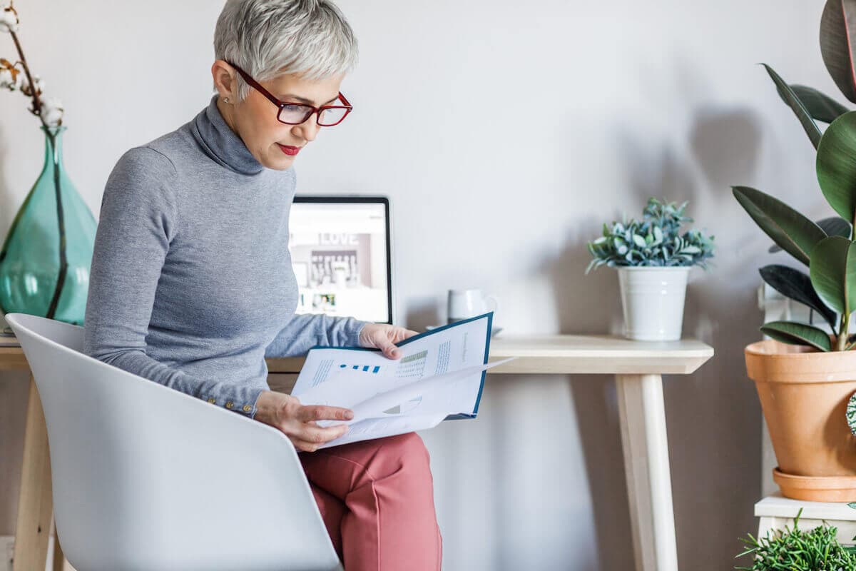 A seated woman with silver hair reviews paperwork.