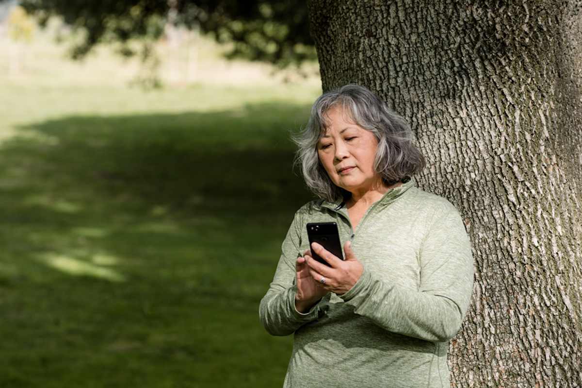 A person in a park looking at her cell phone.