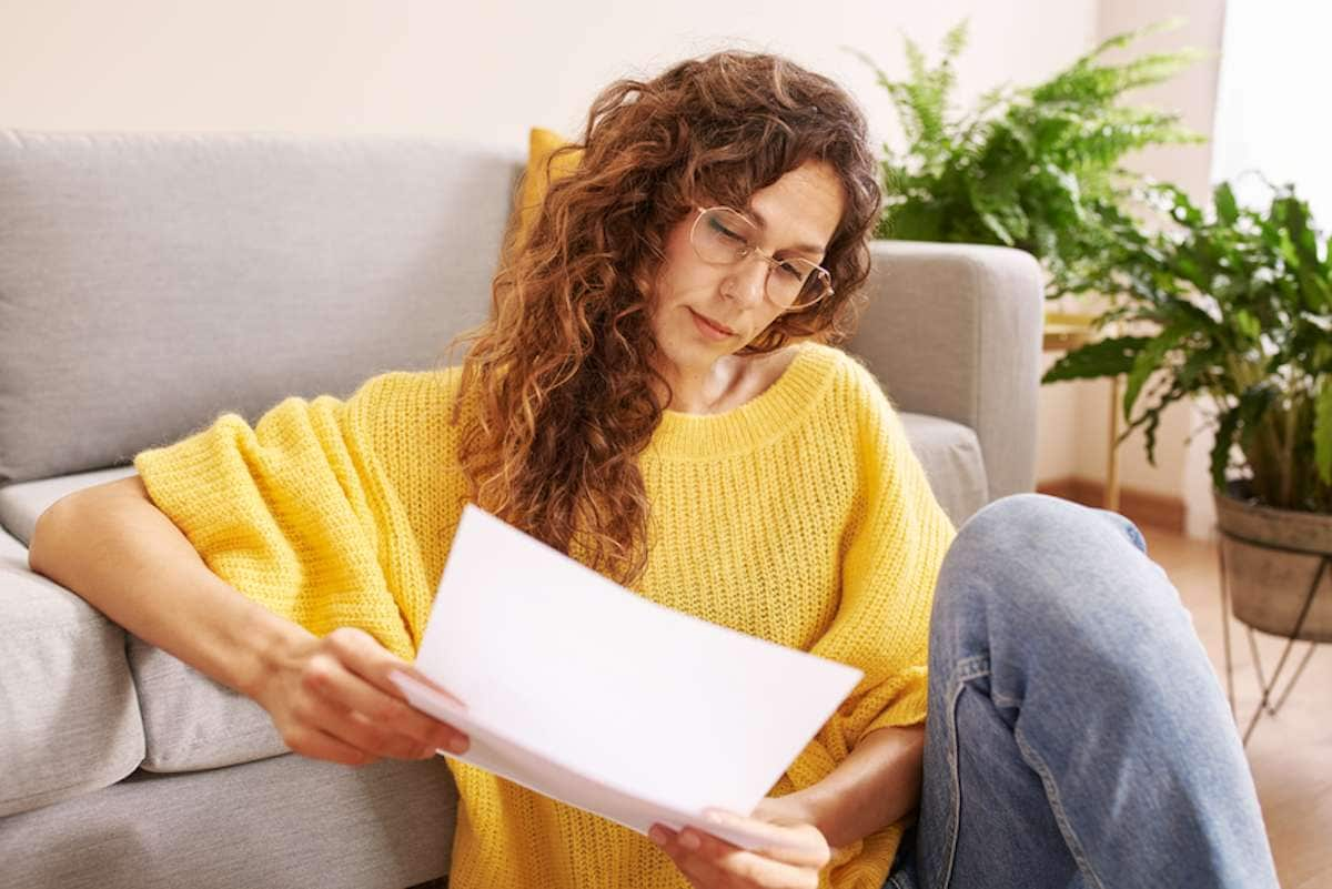 Woman sitting on the floor at home reads a document