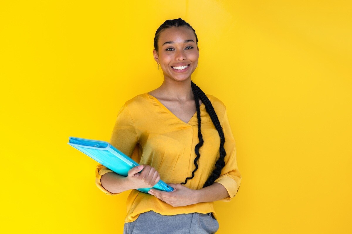 A person wearing holding a blue binder in her hands.