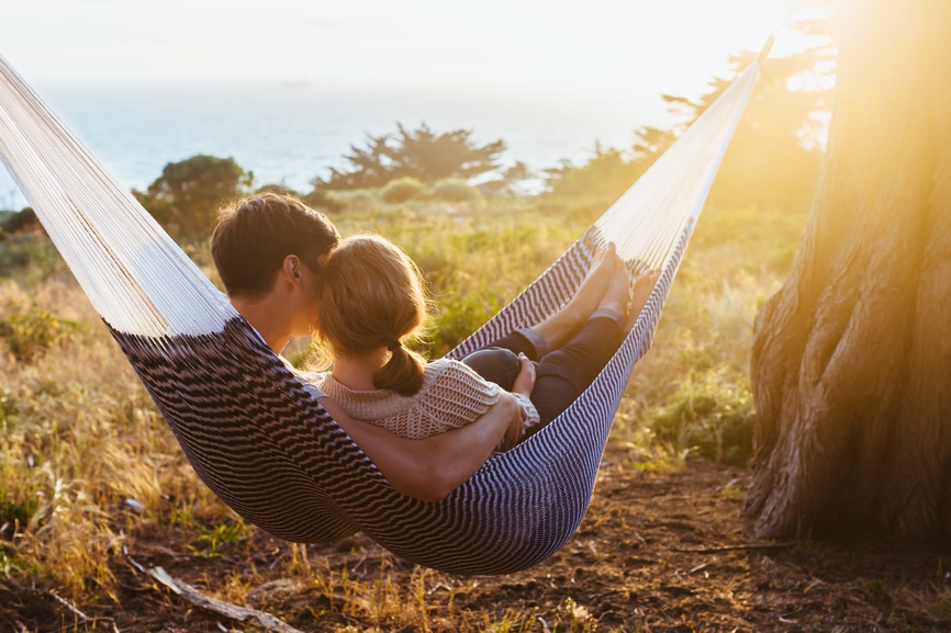 Couple in hammock overlooking water at dusk