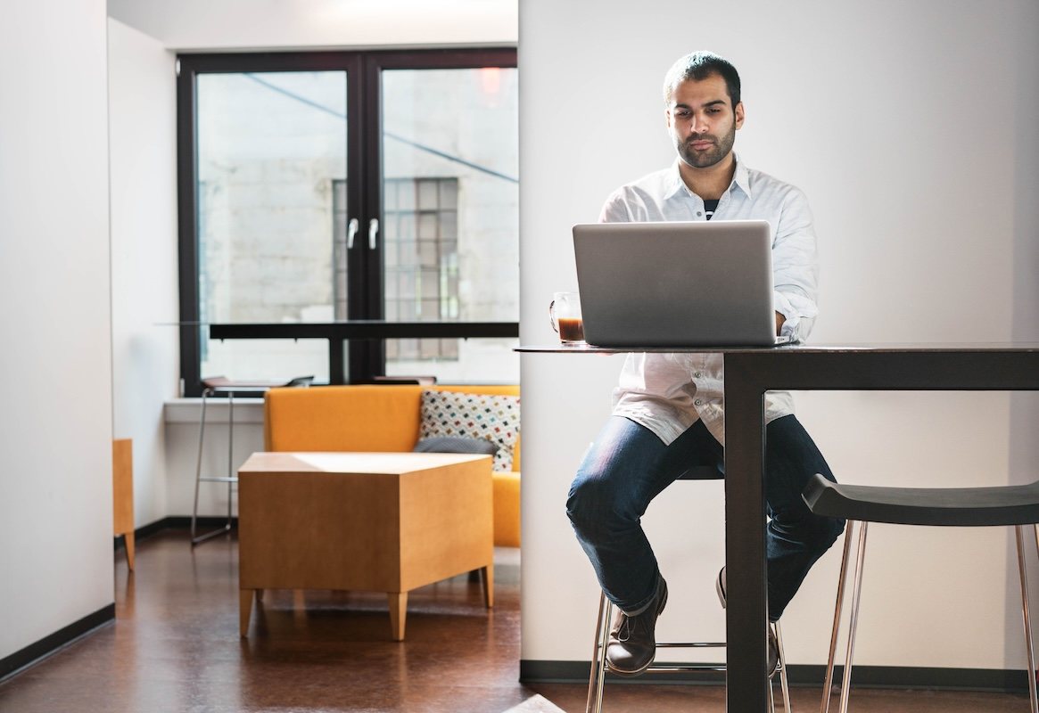 A person sitting at a desk with a laptop and a desktop computer.