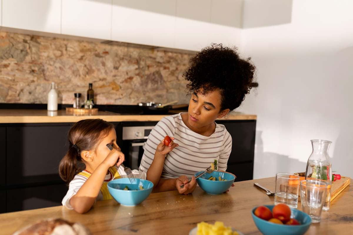 Una madre y su hija pequeña toman un desayuno saludable en la cocina de casa