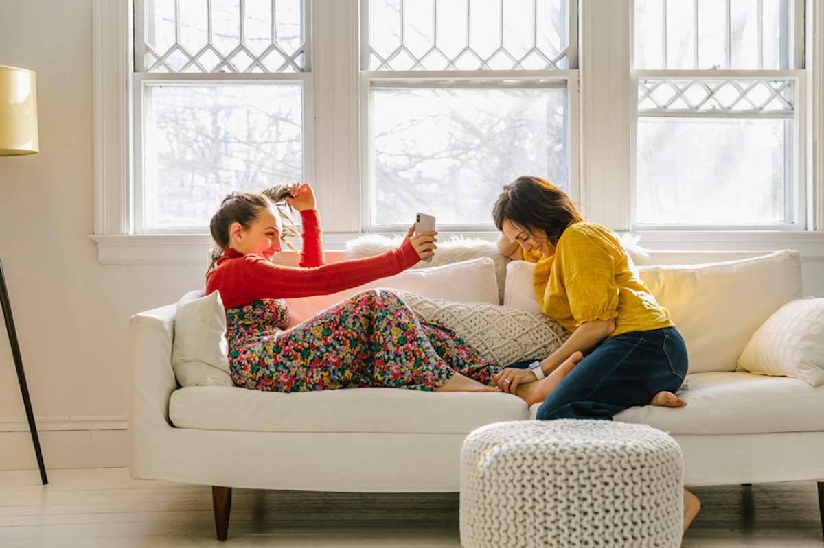 Mother and daughter on a couch sharing a photograph on a cell phone