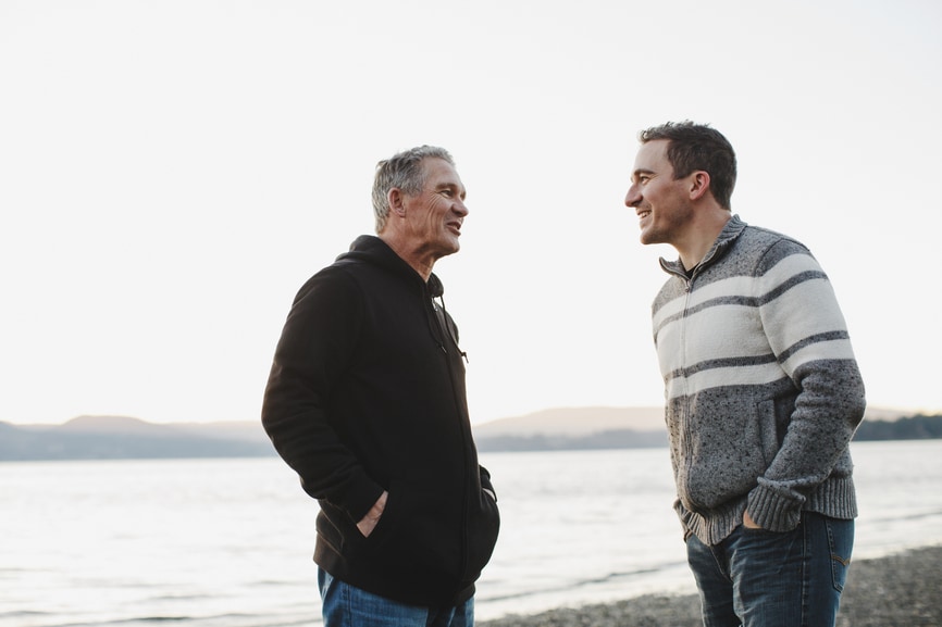 father and son talking on a coast line.