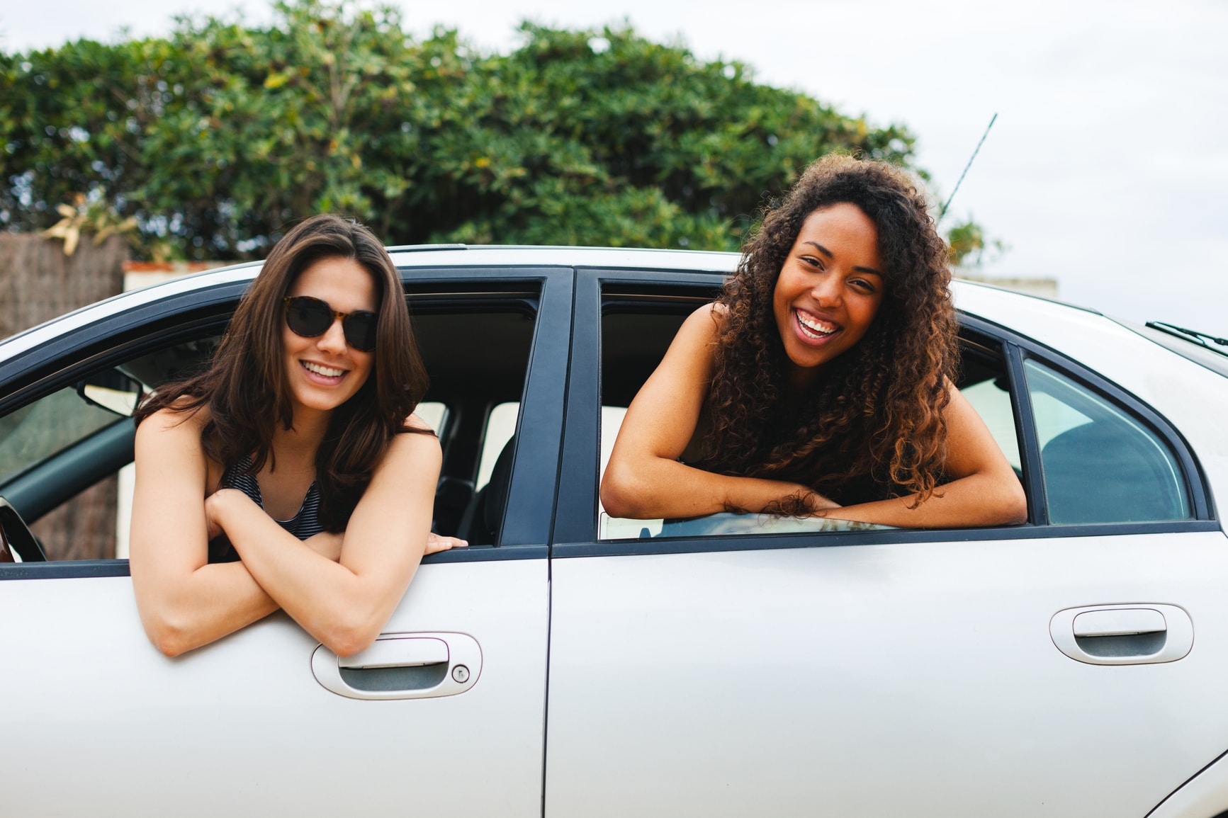 Two girls smiling outside of car window