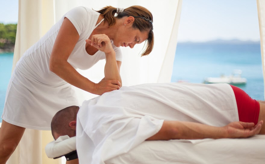 Massage therapist working on a client in a beach setting