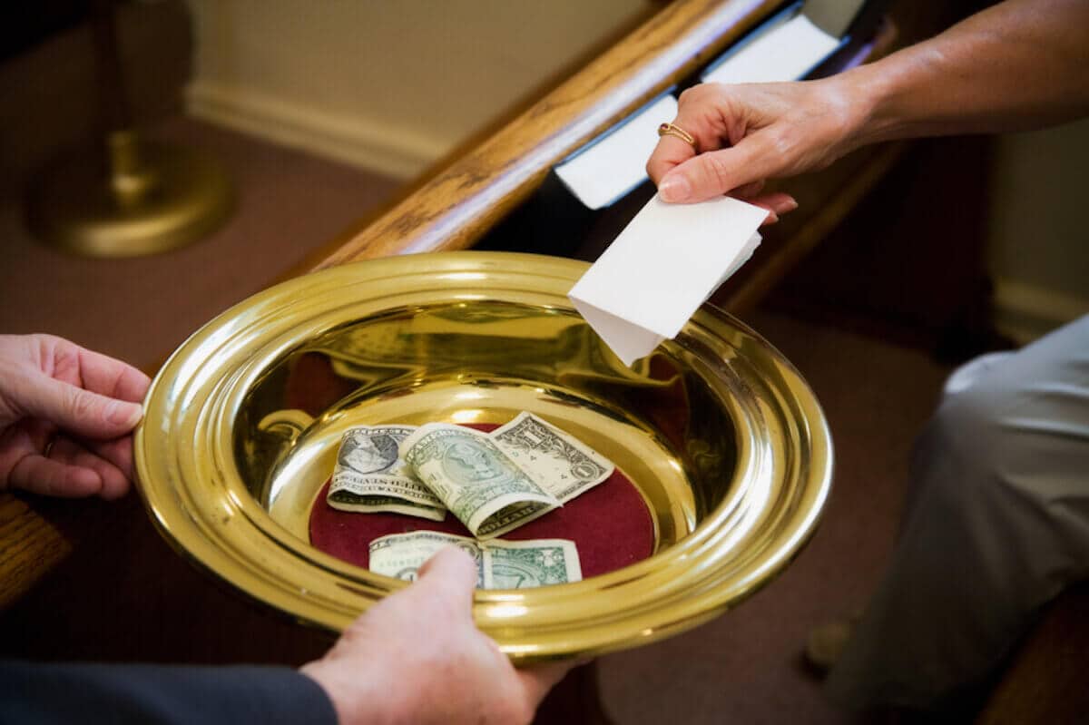 A collection plate is passed around a church pew.