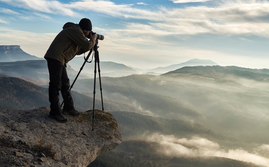 Photographer taking pictures on the edge of a cliff