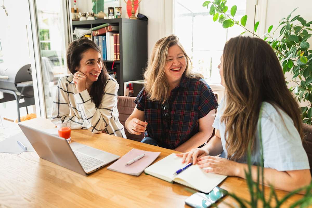 Three people sitting at a table with laptops.