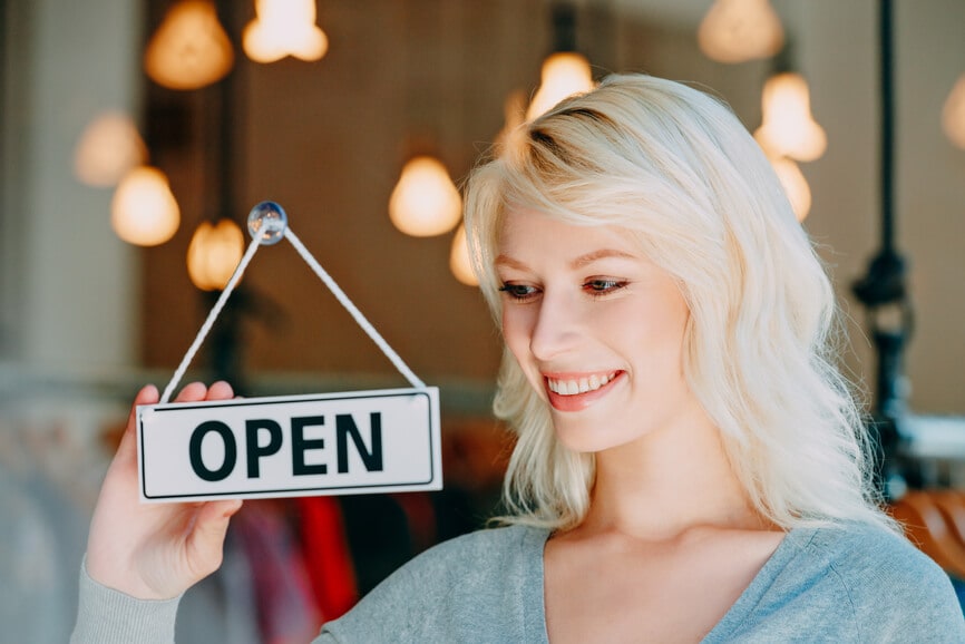 Small business owner flipping her shop sign to say Open