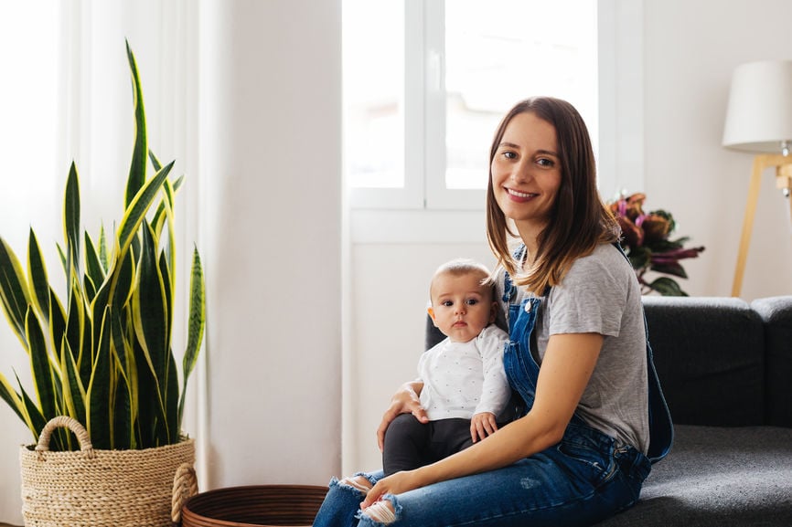 Young woman smiling and holding an infant in her lap