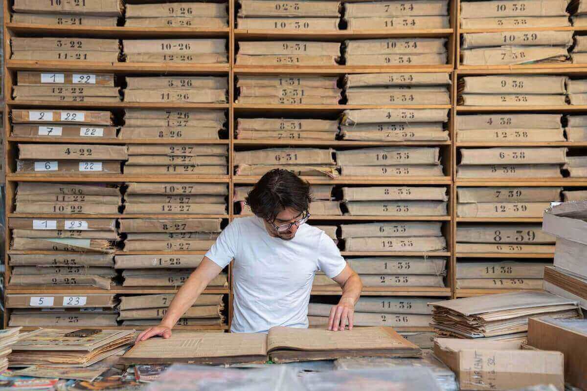 A man reads newspapers in an archive.