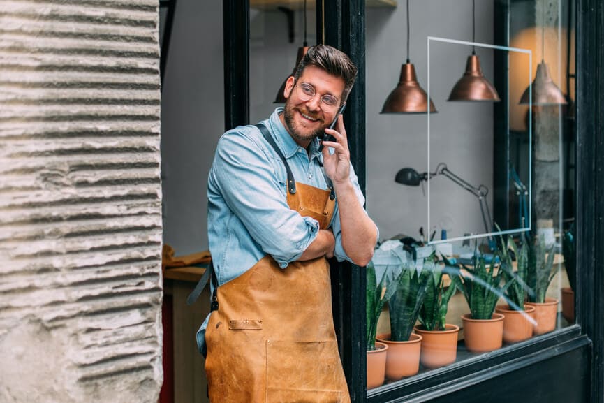 Small business owner talking on the phone outside his workshop.