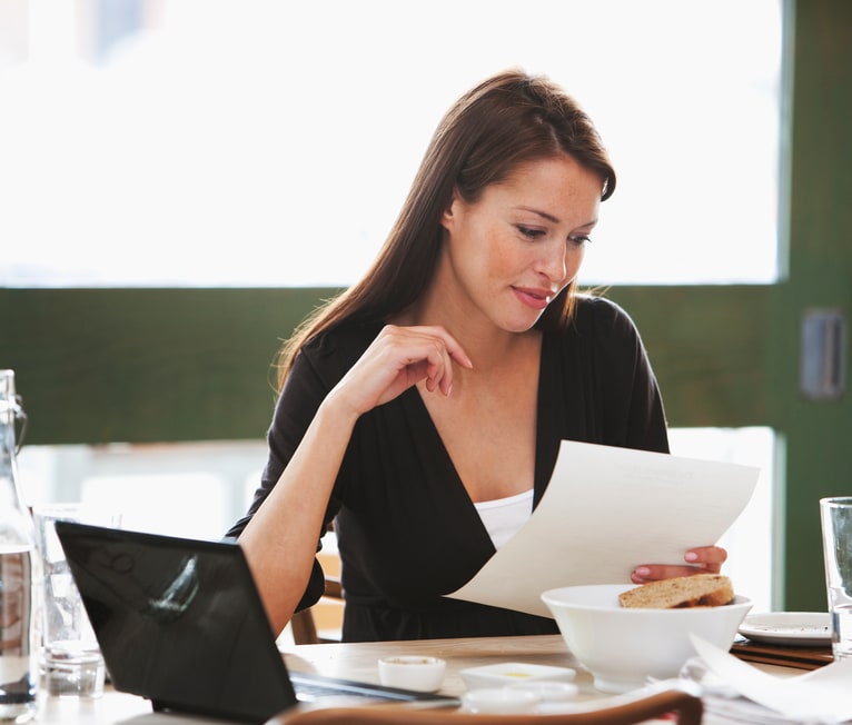 Woman reading paper at the computer