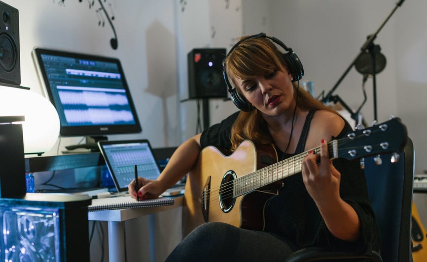 Woman recording guitar in her home sound studio