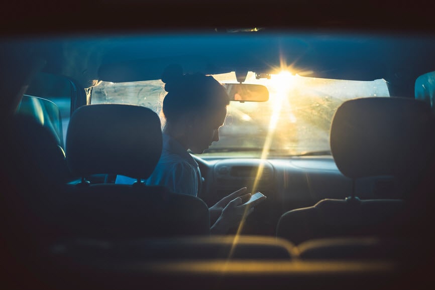 Woman on smartphone in car at dusk