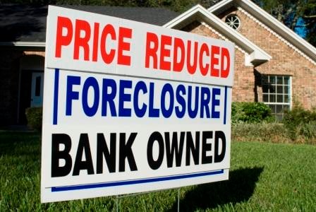 A foreclosure sale sign in a yard in front of a house