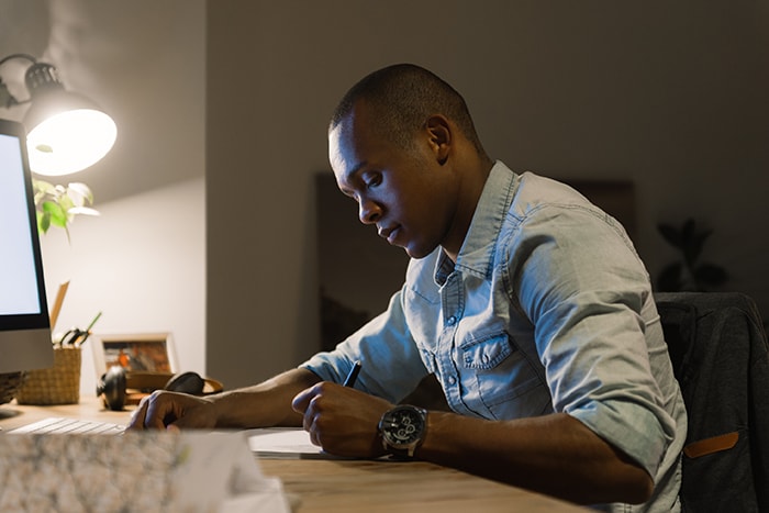 Man writing at computer desk